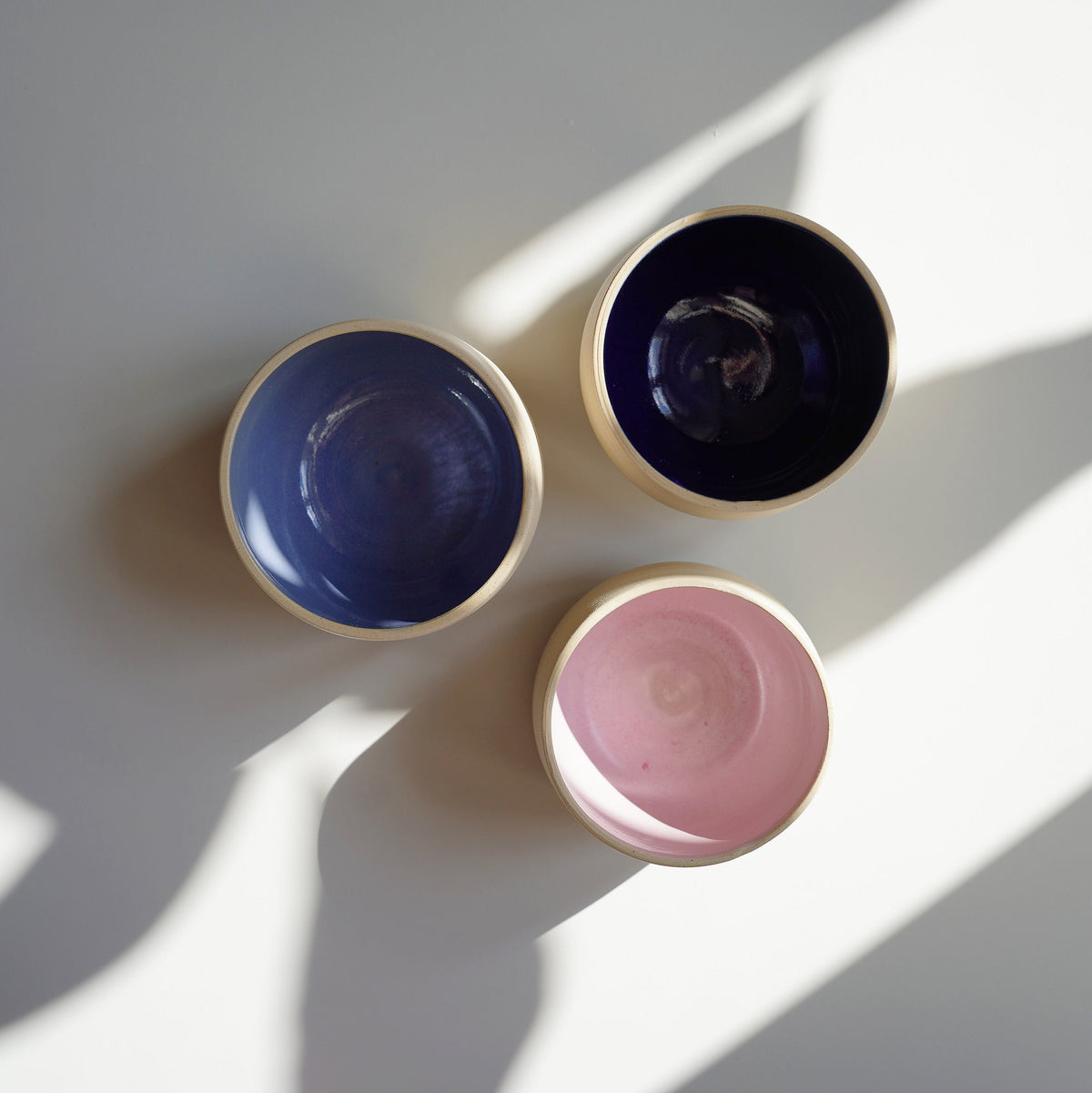 Drei Kaffee-Becher von oben fotografiert, blaue und rosafarbene Glasur auf der Innenseite